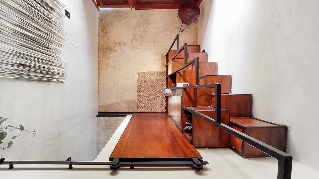 Escalera de madera con barandillas de metal oscuro en una habitación de estilo rústico.