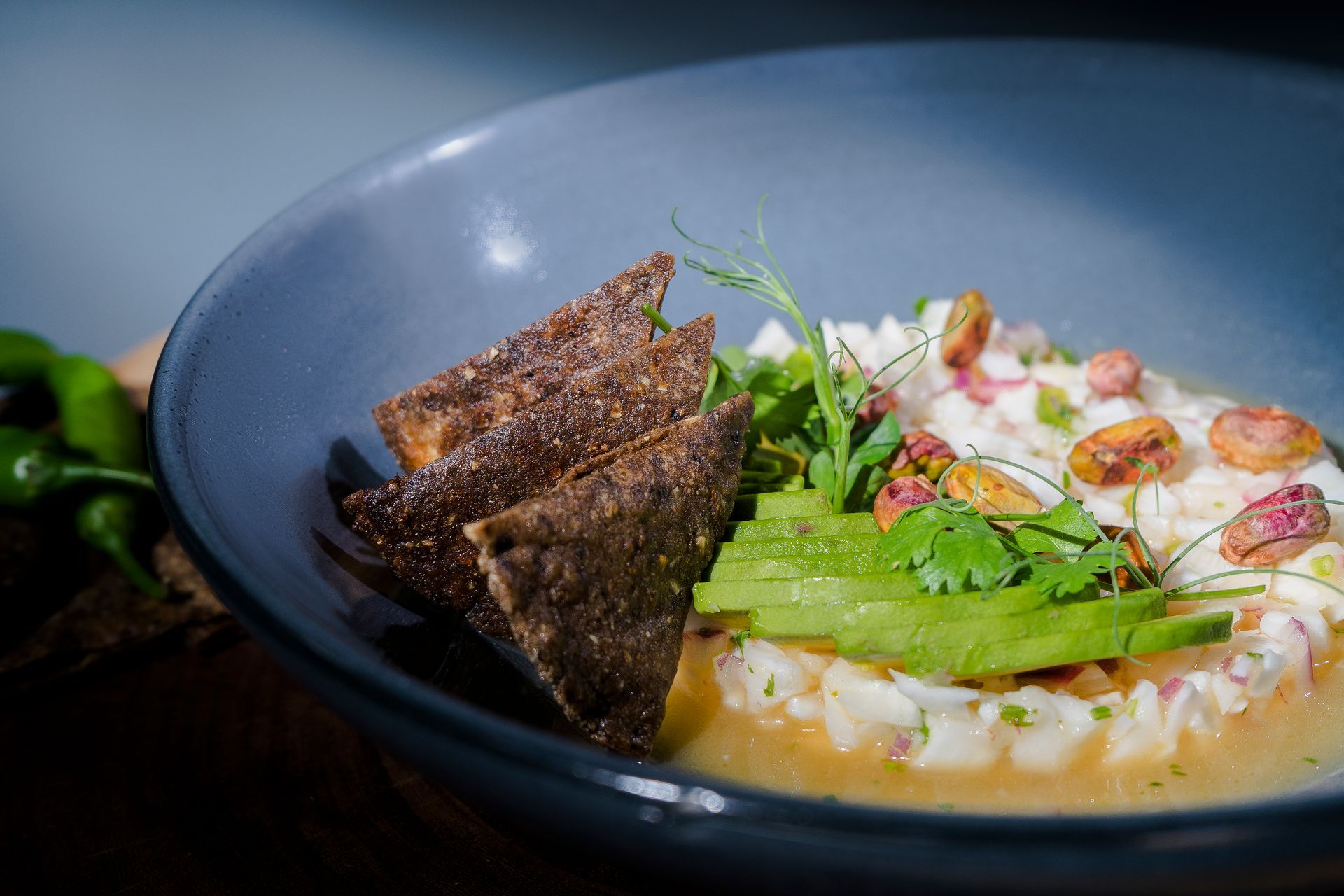 Un tazón de ceviche con rodajas de aguacate, cilantro y totopos.