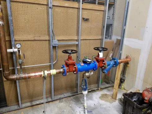 Blue and red plumbing valves and pipes installed in an unfinished wall space