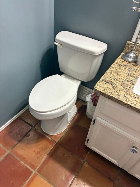 Copper plumbing pipes in a damaged wall with standing water on the floor.