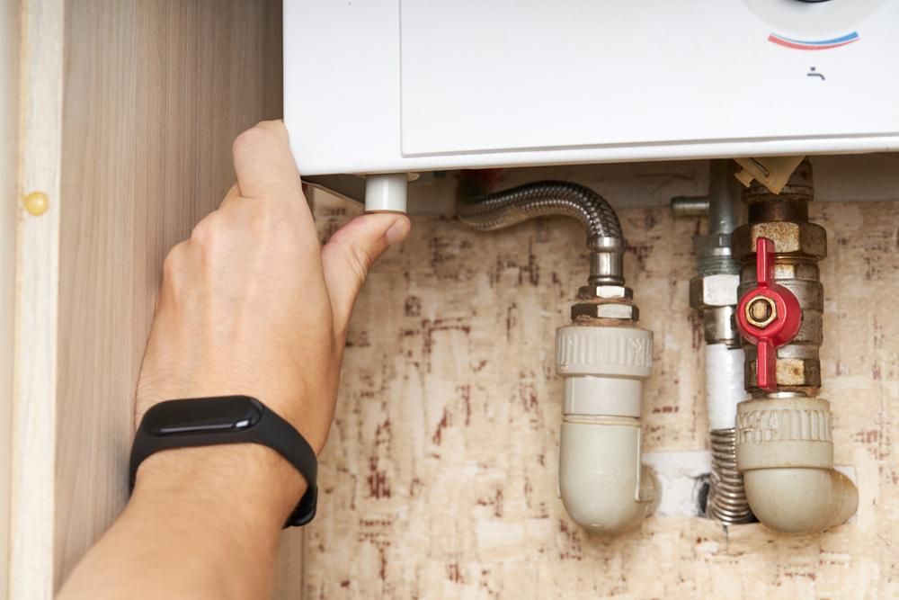 A Person is Fixing a Water Heater With a Smart Watch on Their Wrist — Jet 'N' Drain Pty Ltd In Kawungan, QLD