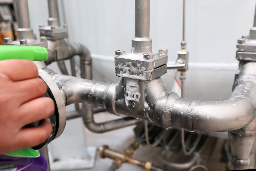 A Person is Cleaning a Stainless Steel Pipe With a Spray Bottle — Jet 'N' Drain Pty Ltd In Kawungan, QLD