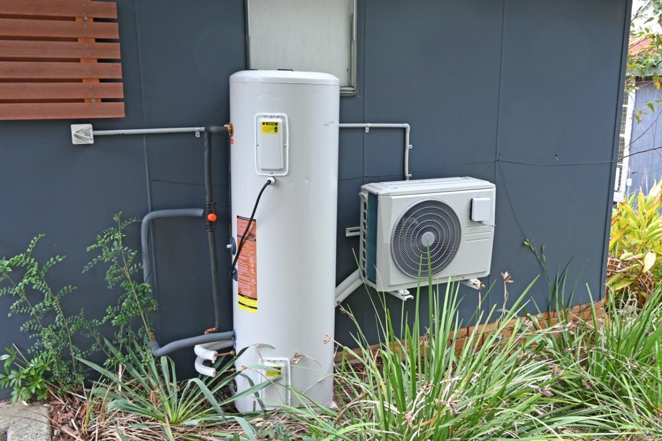 A Water Heater is Attached to the Side of a Building Next to an Air Conditioner — Jet 'N' Drain Pty Ltd In Kawungan, QLD