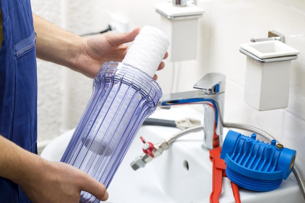 A Person is Holding a Water Filter in Front of a Sink — Jet 'N' Drain Pty Ltd In Kawungan, QLD