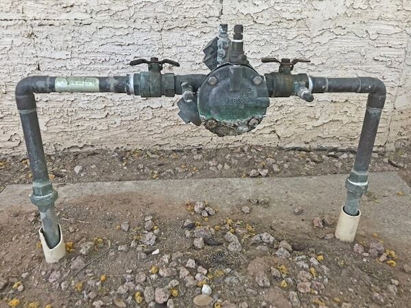 A Water Meter is Sitting on the Ground Next to a Brick Wall — Jet 'N' Drain Pty Ltd In Kawungan, QLD