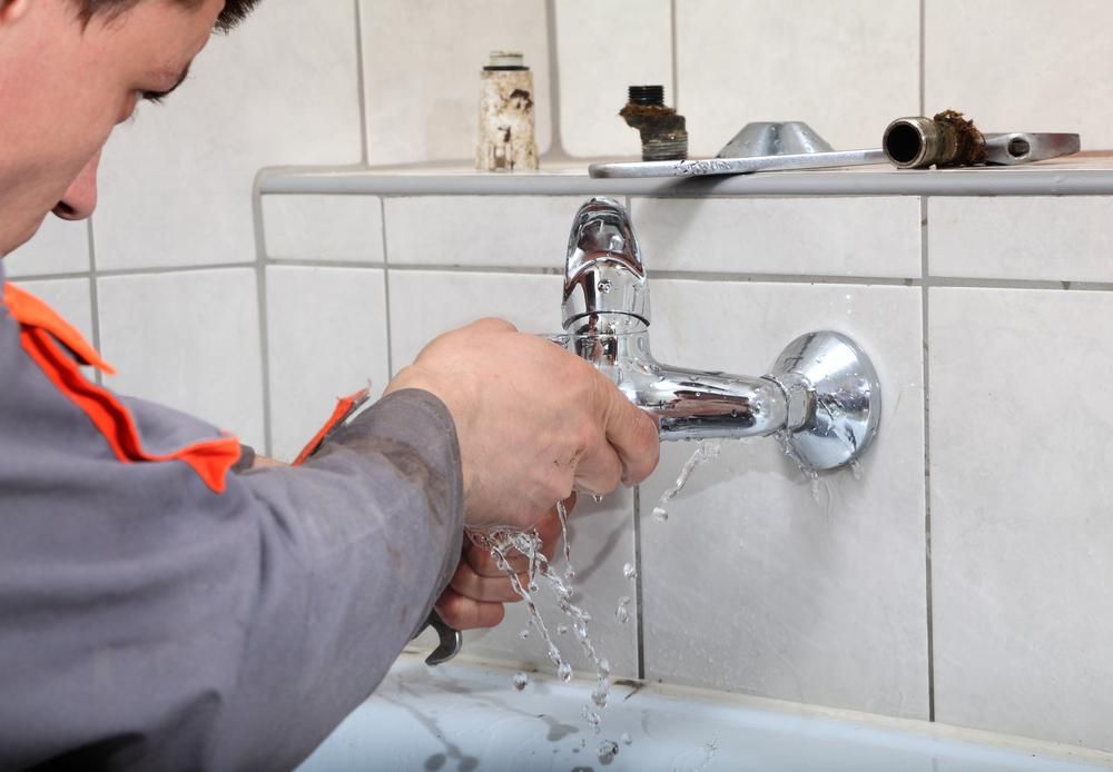 A Man is Fixing a Faucet in a Bathroom — Jet 'N' Drain Pty Ltd In Kawungan, QLD