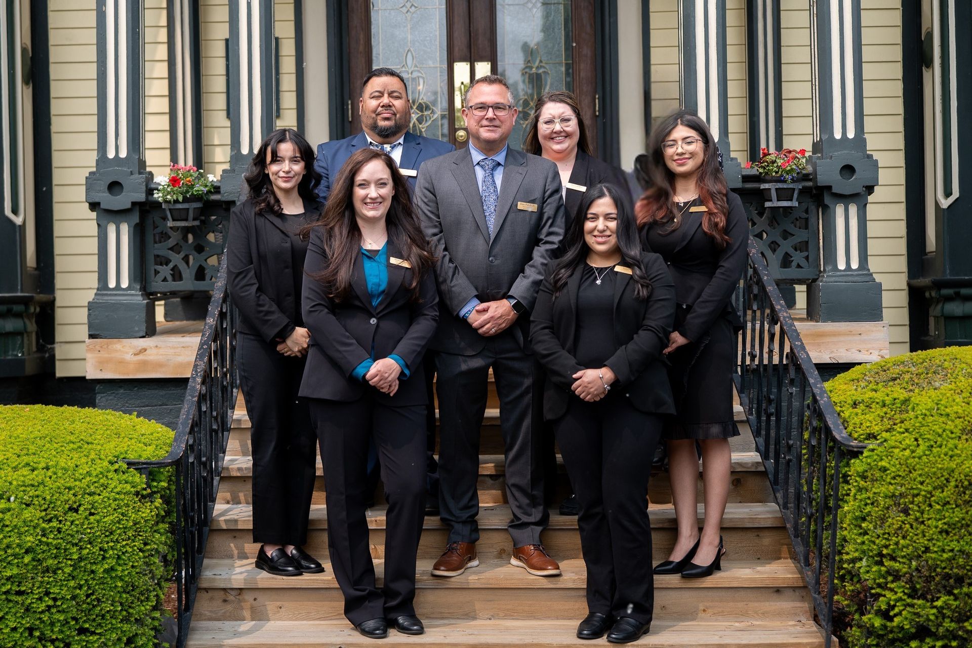 Group posing on outdoor steps in front of a building, dressed in business attire.