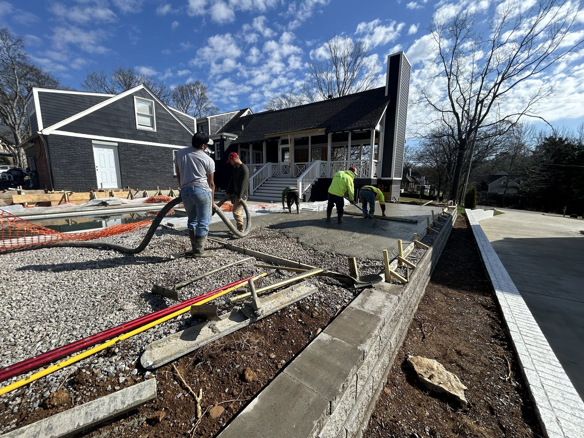 Workers laying a gravel path and curb beside a house under construction on a sunny day