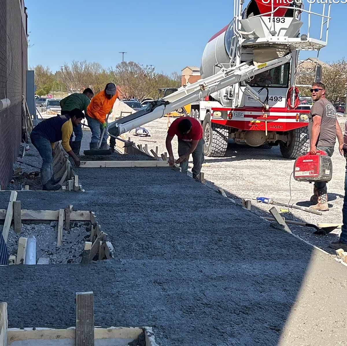Construction workers pouring concrete sidewalk from a truck.