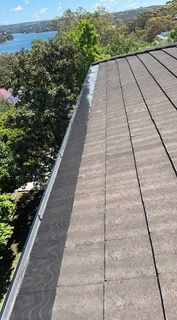 A roof with a gutter on it and a view of a lake.