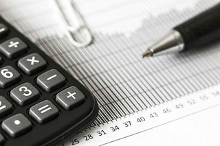 Person using a calculator with a pen, working on documents.