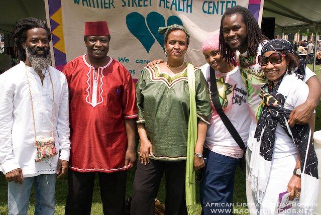 Six people pose together at a health center event, standing in front of a banner.