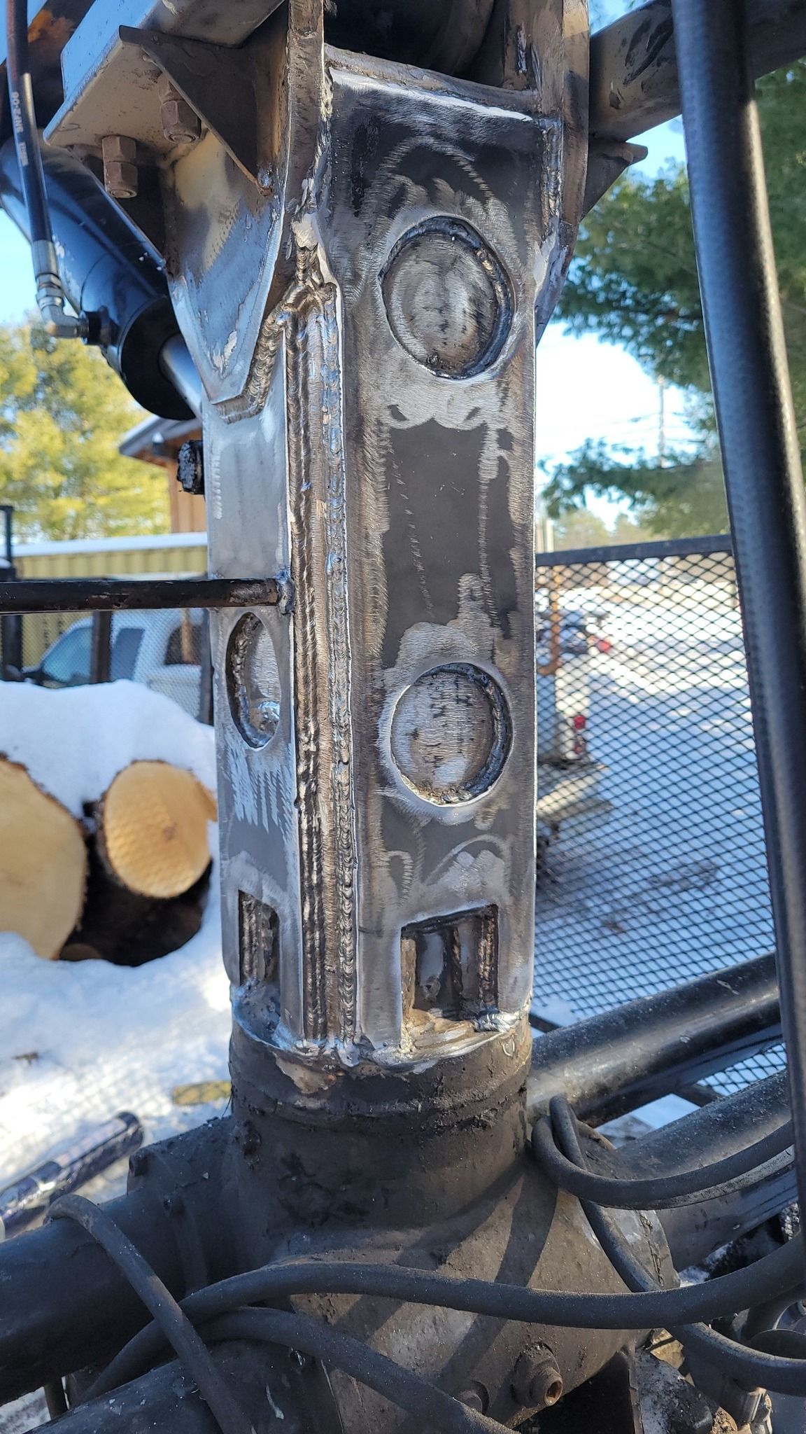 A close up of a metal pole with a bunch of logs in the background.