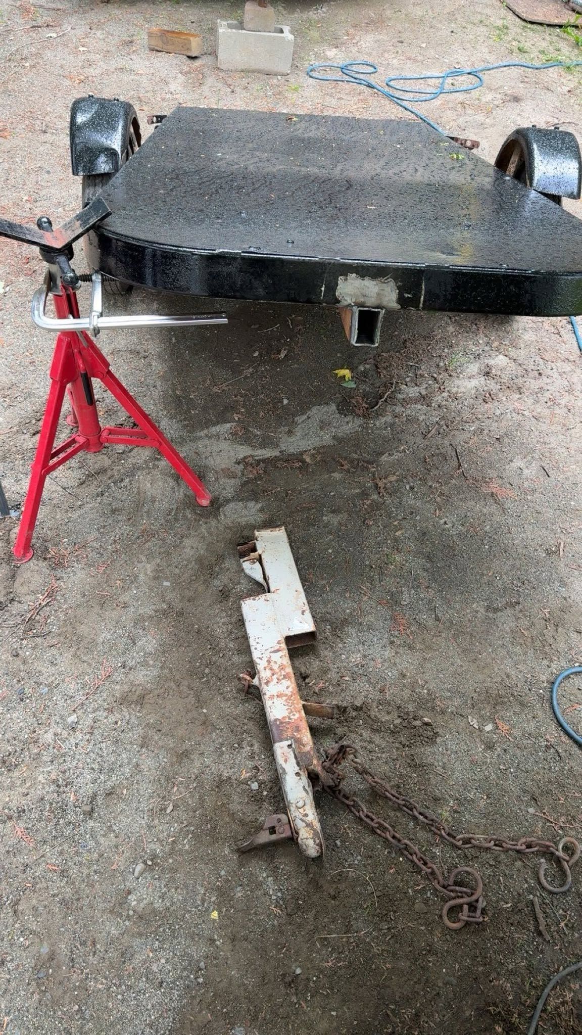 A trailer is sitting on the ground next to a red tripod.