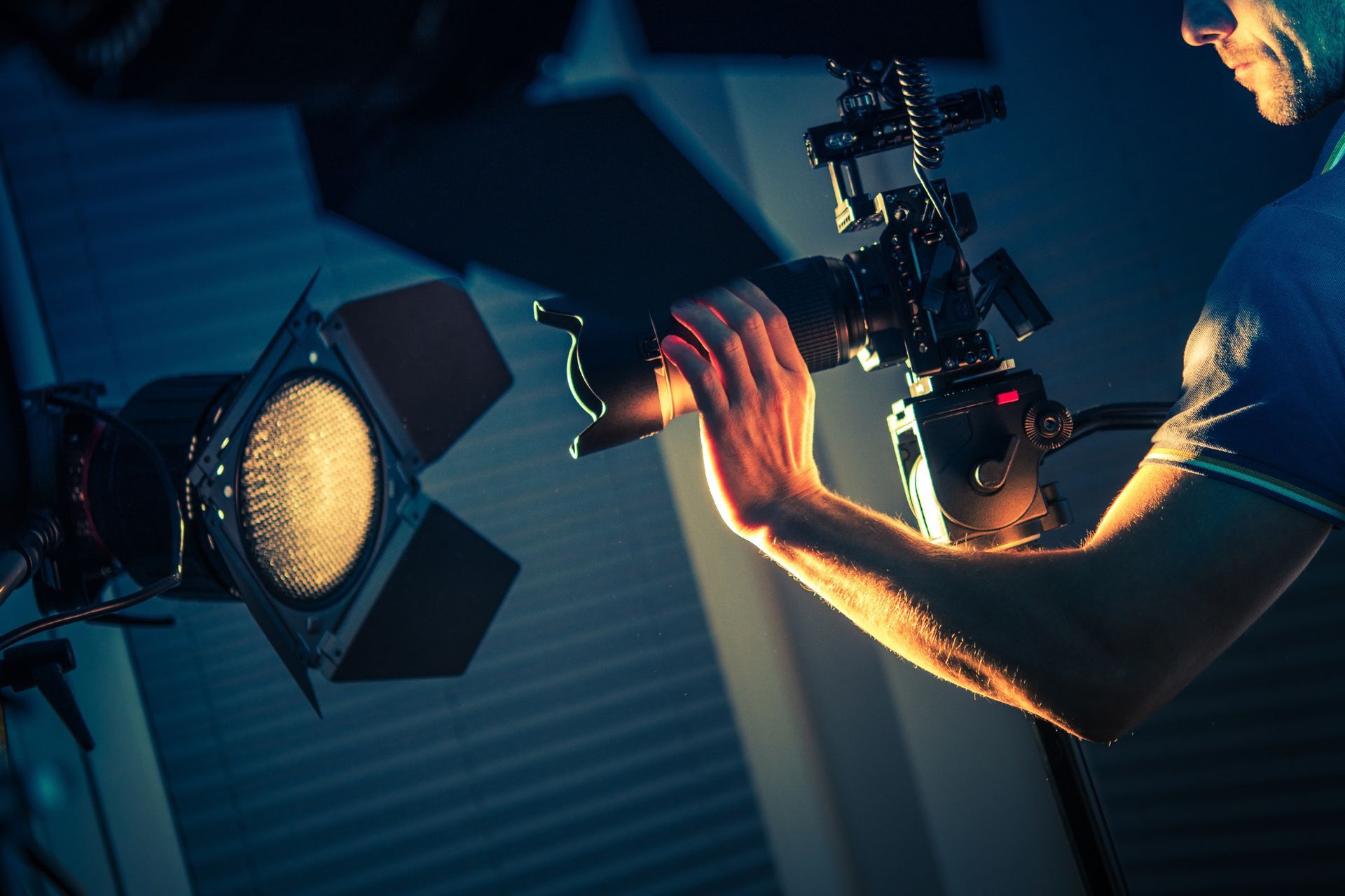 Photographer adjusting a camera on a studio light, with a bright softbox glowing in a dark setting