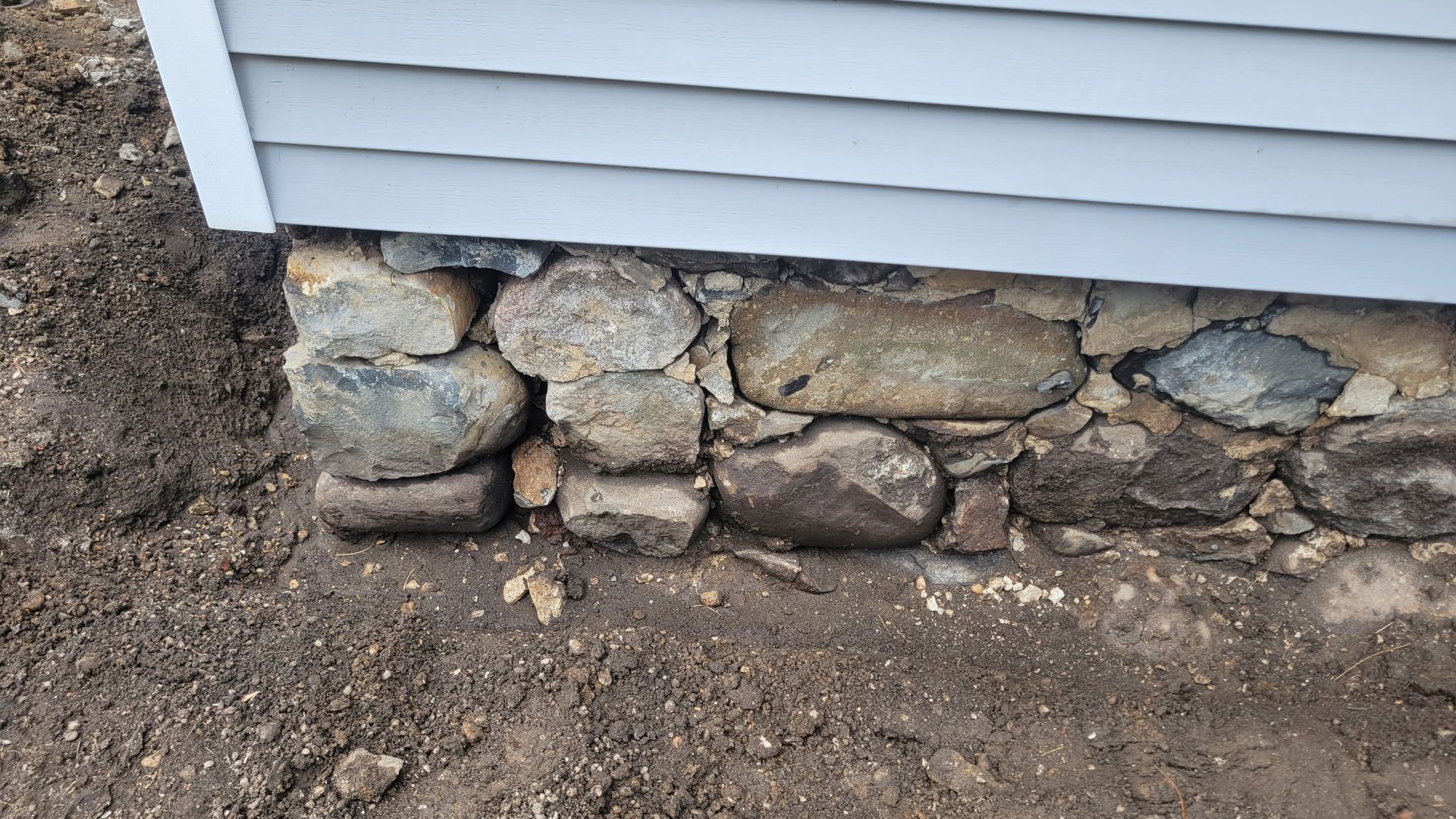 A stone wall is being built next to a house.
