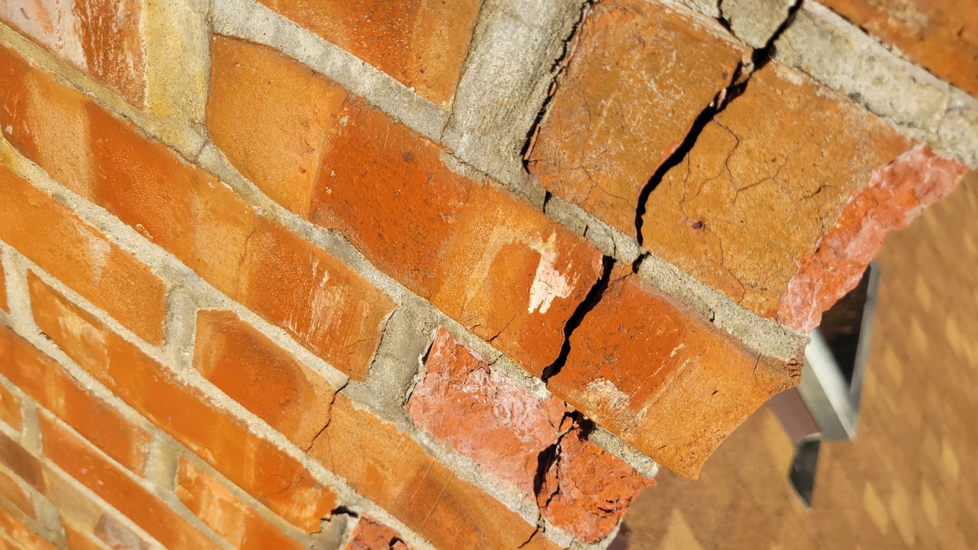 Close-up of a brick archway with cracks in the bricks and mortar.