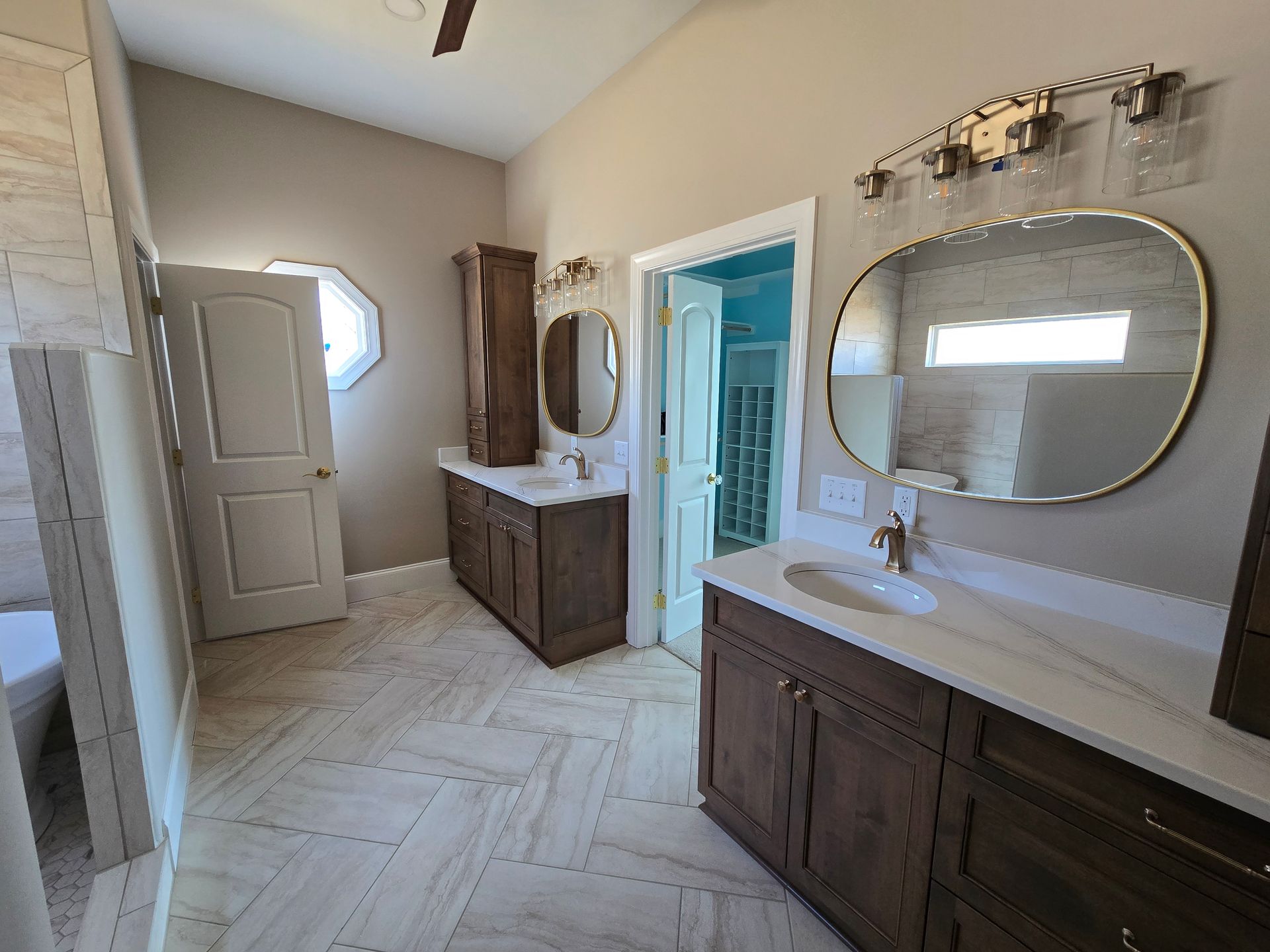 Bright bathroom with two vanities, round mirrors, white tile floor, and an open door to a shower area