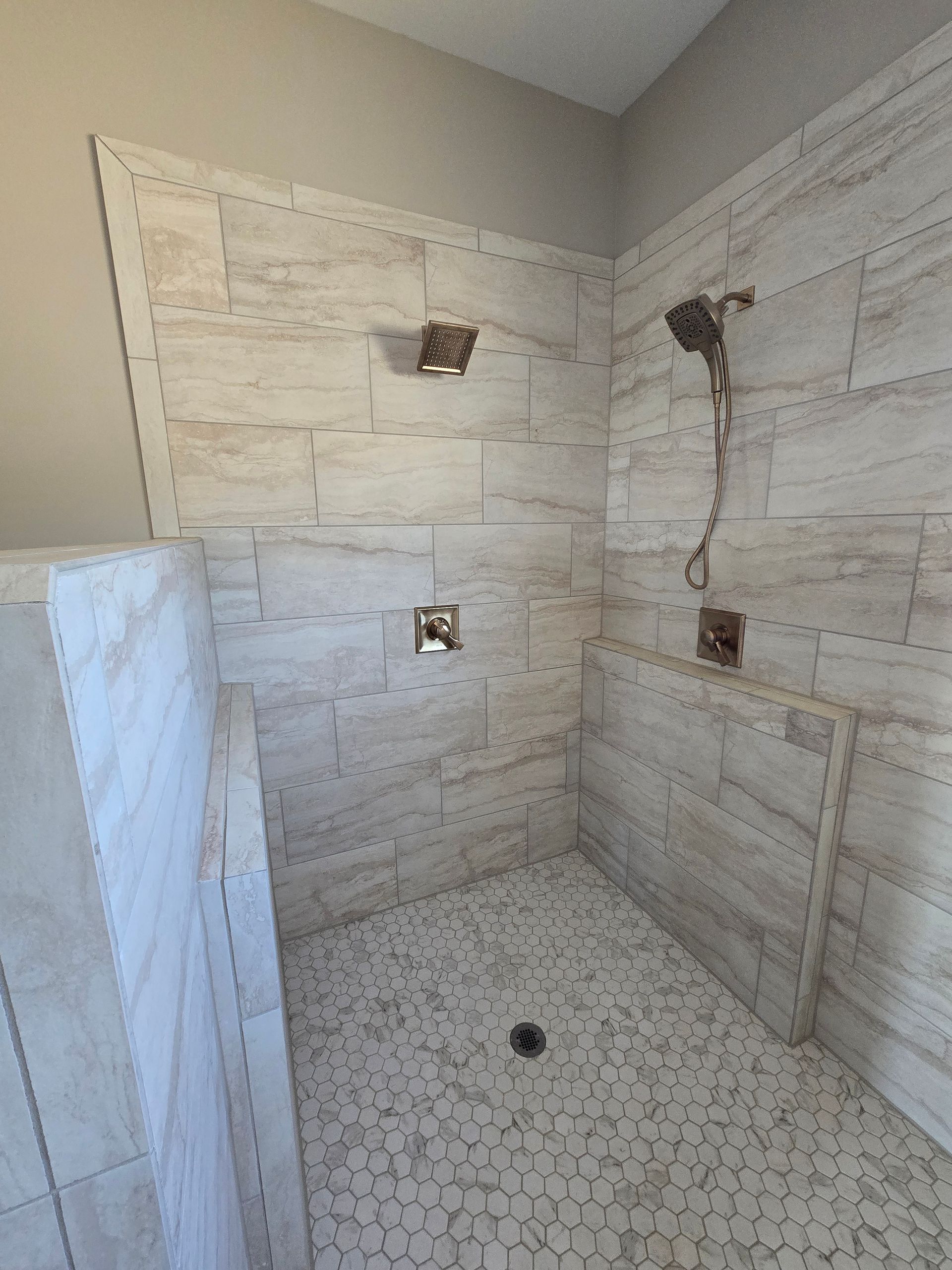 Bare unfinished bathroom with tiled shower walls, plumbing openings, and hexagon floor tile