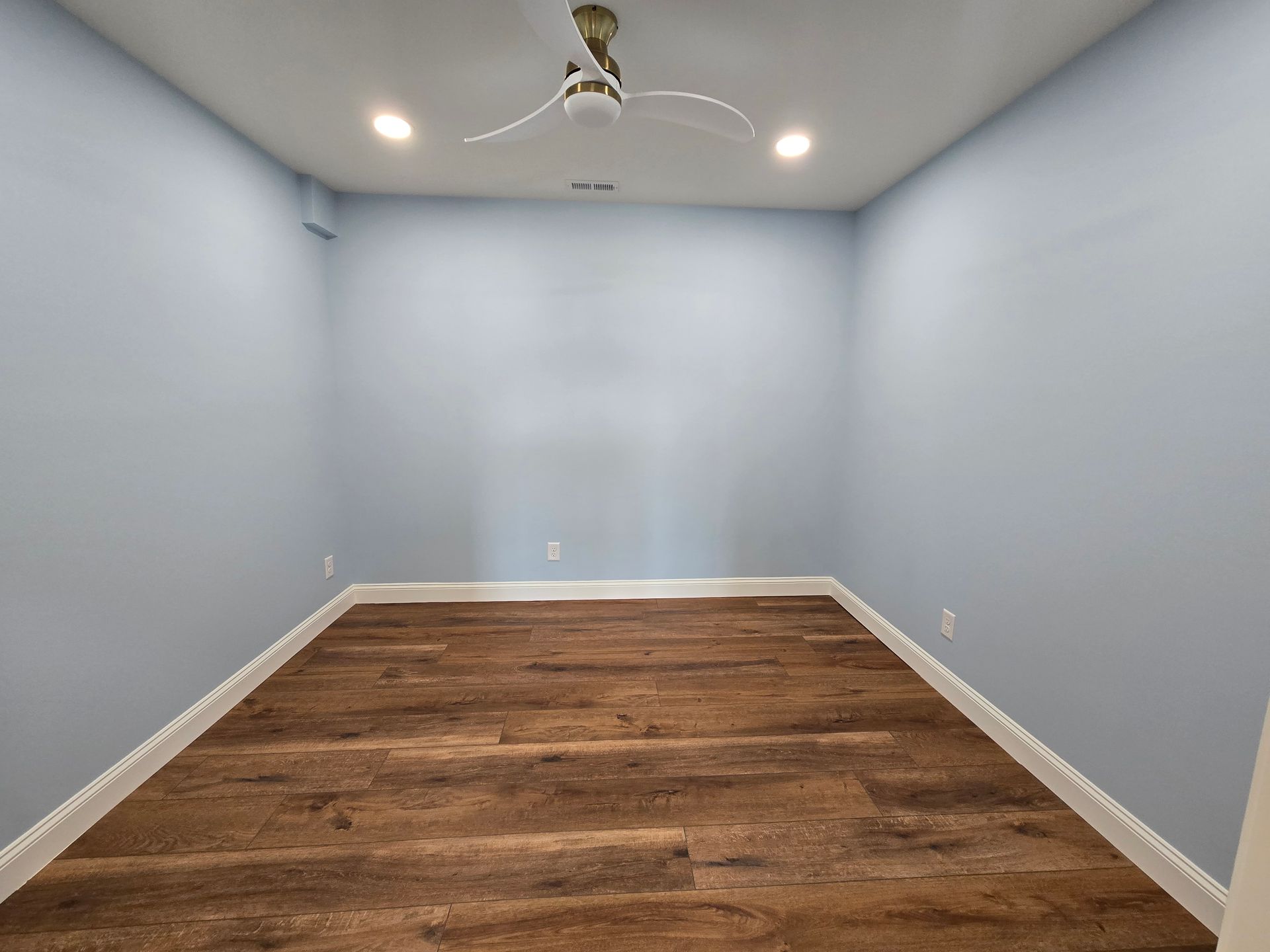 Empty small room with light gray walls, wood-look flooring, recessed lights, and a ceiling fan