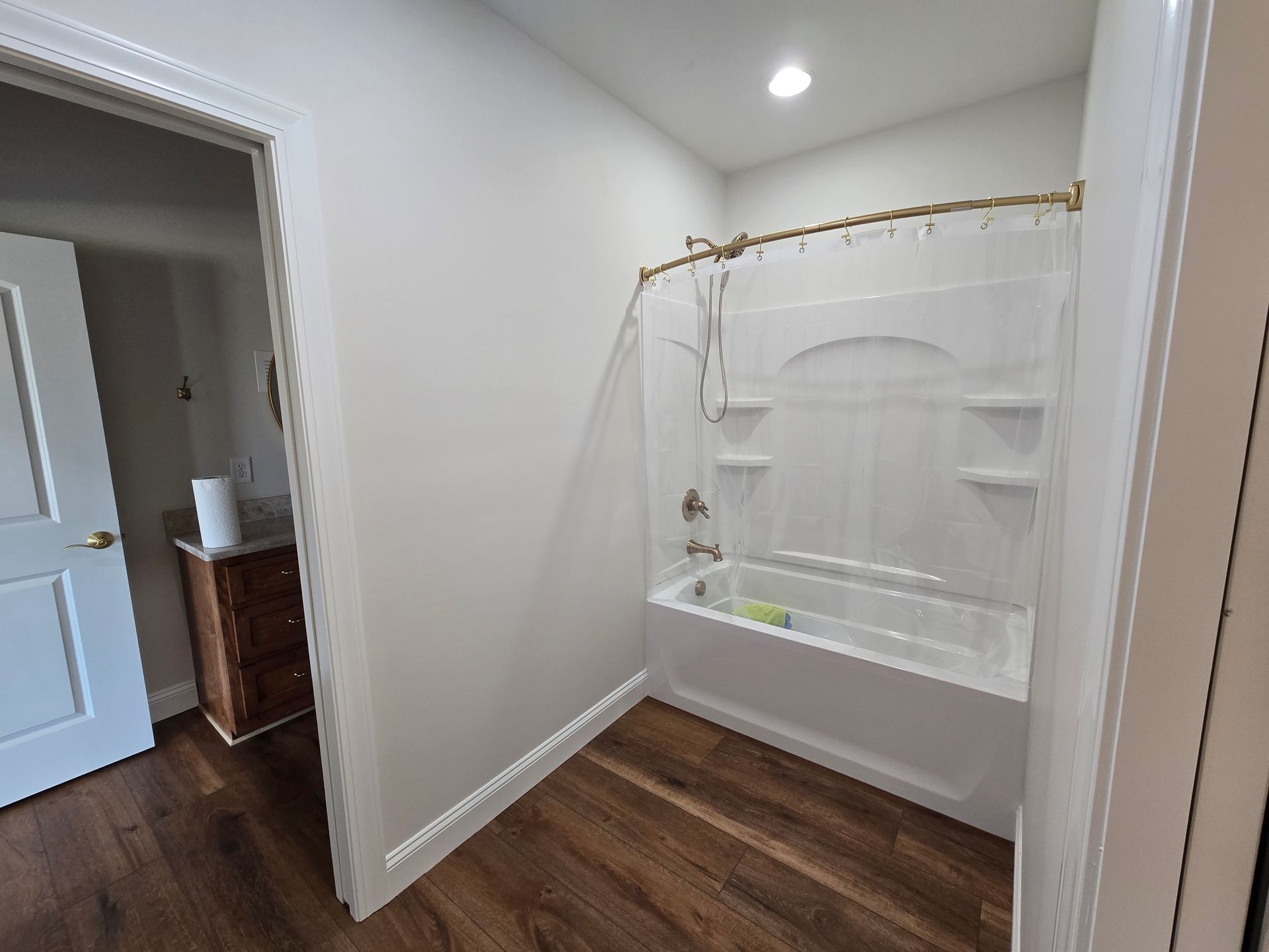 Small empty room with wood floors, white walls, and an open closet nook with a shower curtain rod.