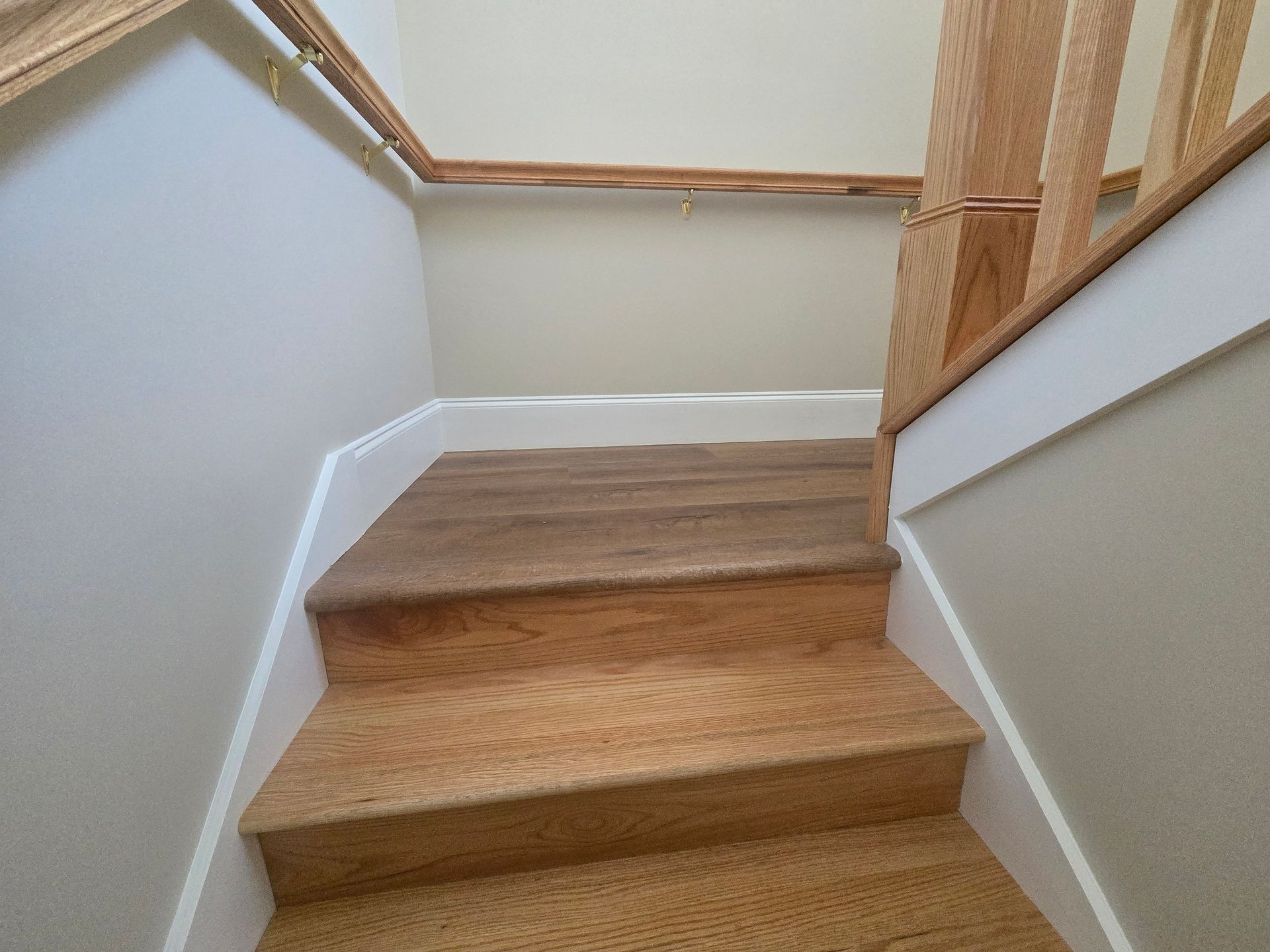 Carpeted staircase with white walls and wooden handrails in a narrow hallway