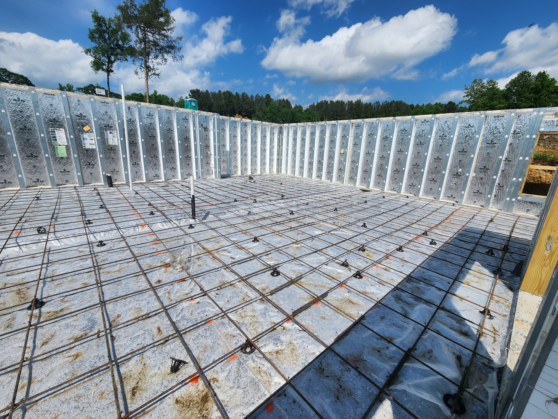 Concrete foundation slab with steel rebar walls under construction on a sunny day