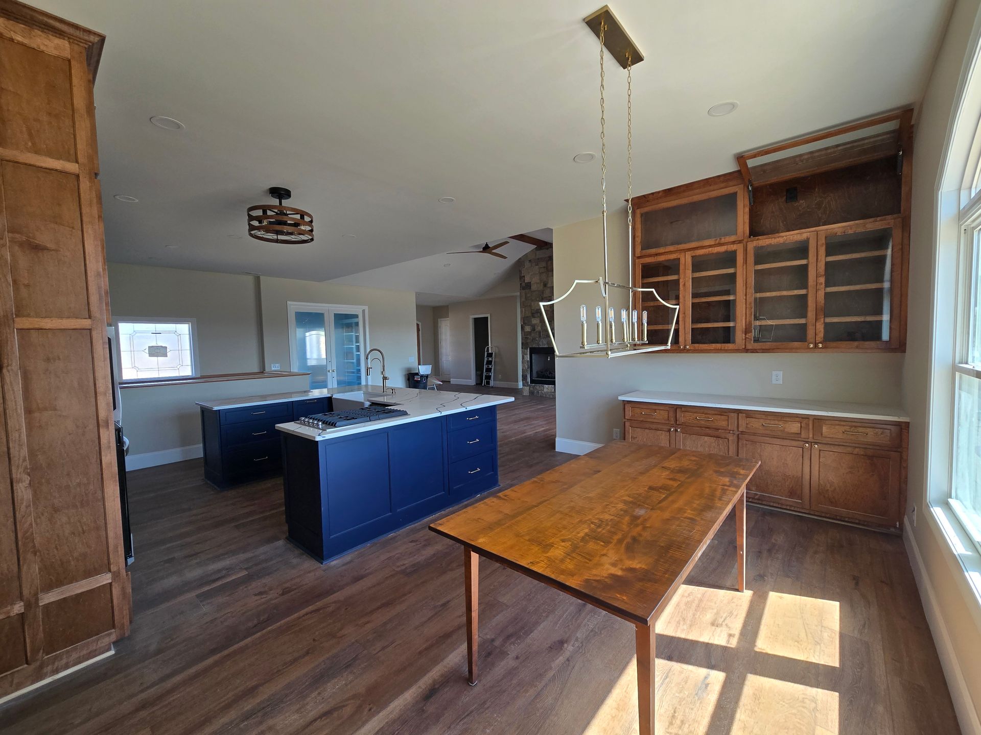 Empty kitchen with blue island cabinets, wood floors, and built-in hutch in a bright room