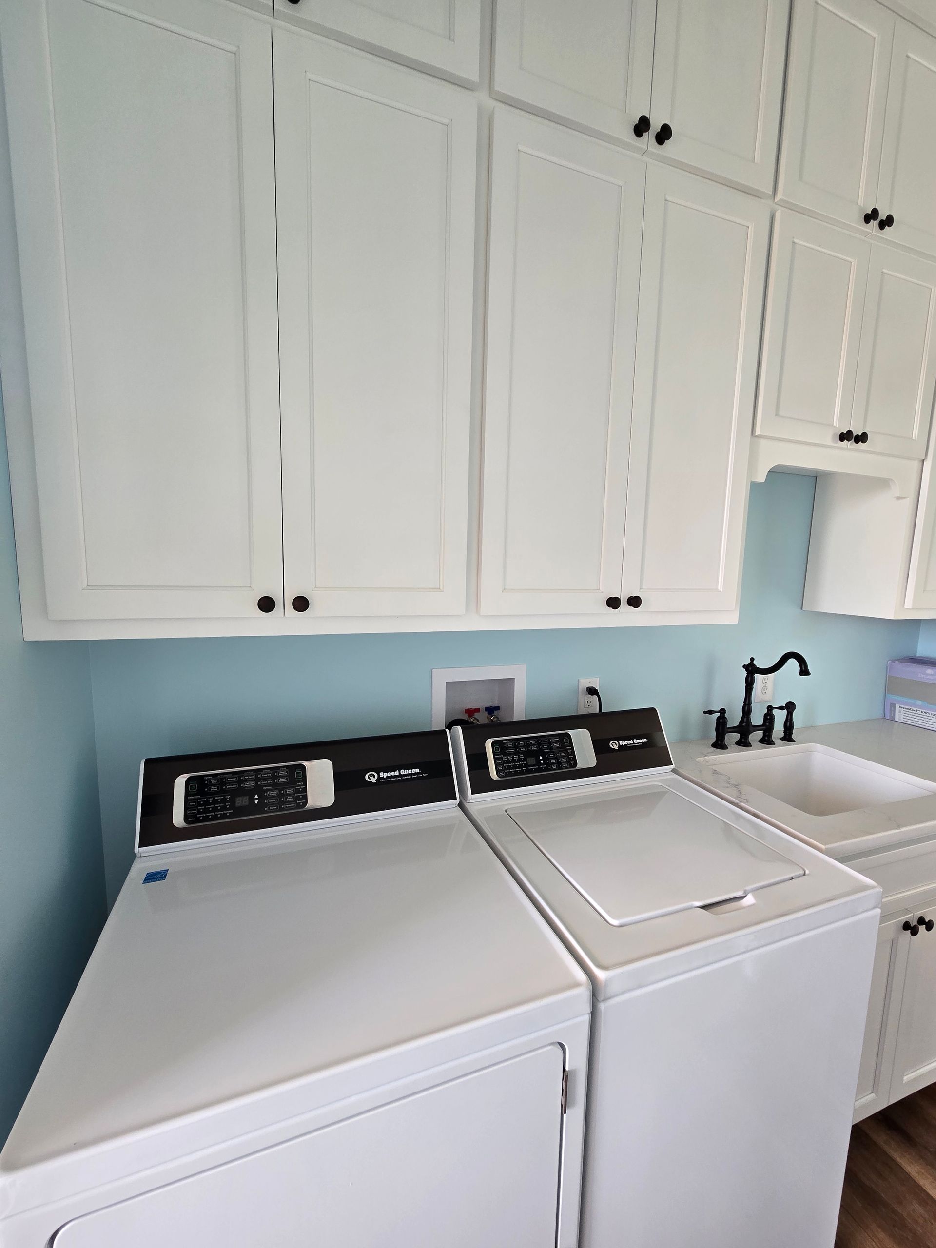 Laundry room with a washer, dryer, white cabinets, and a sink beneath a window