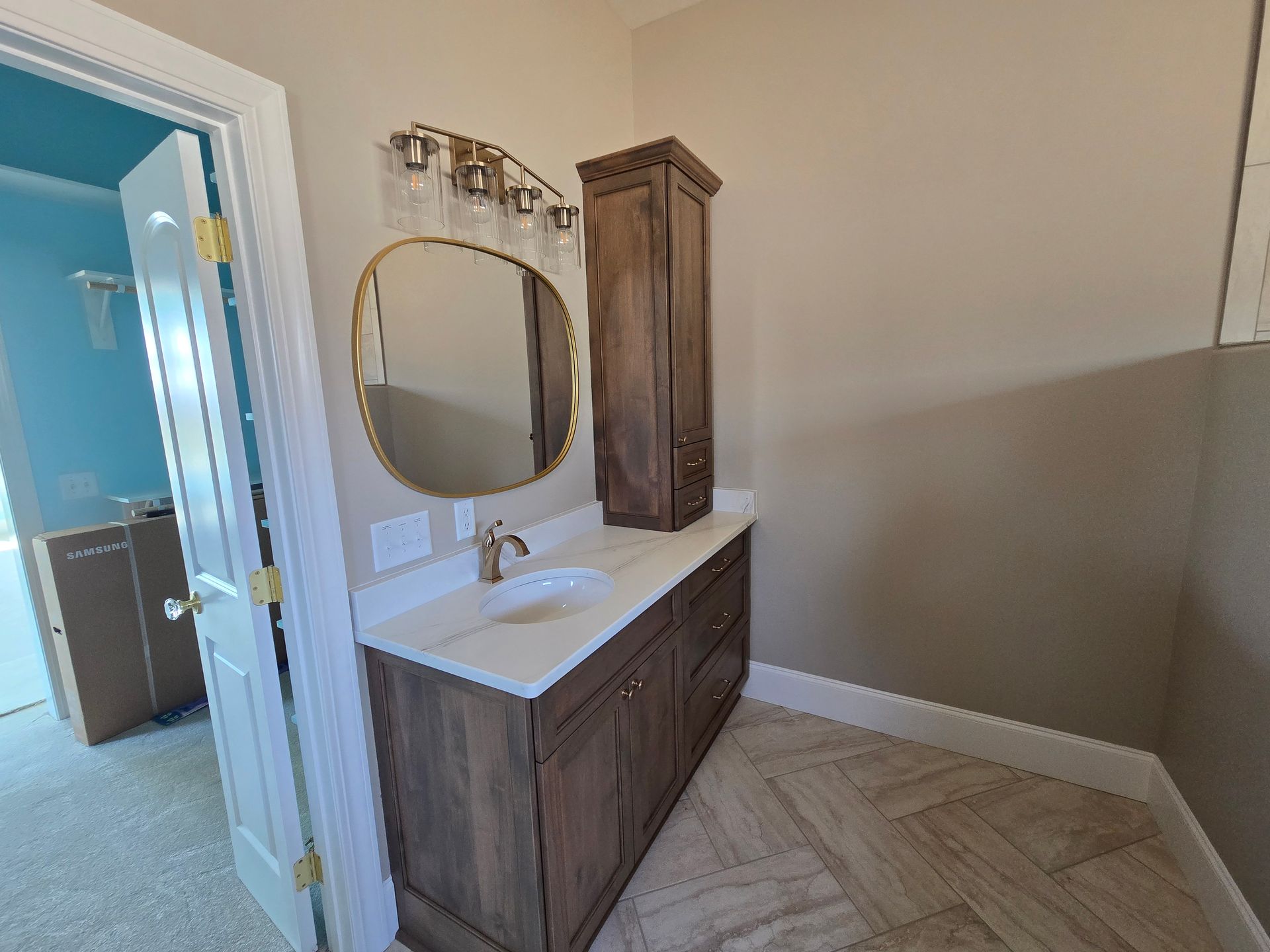 Bathroom vanity with oval mirror, wood cabinets, and hex tile floor in a light beige room