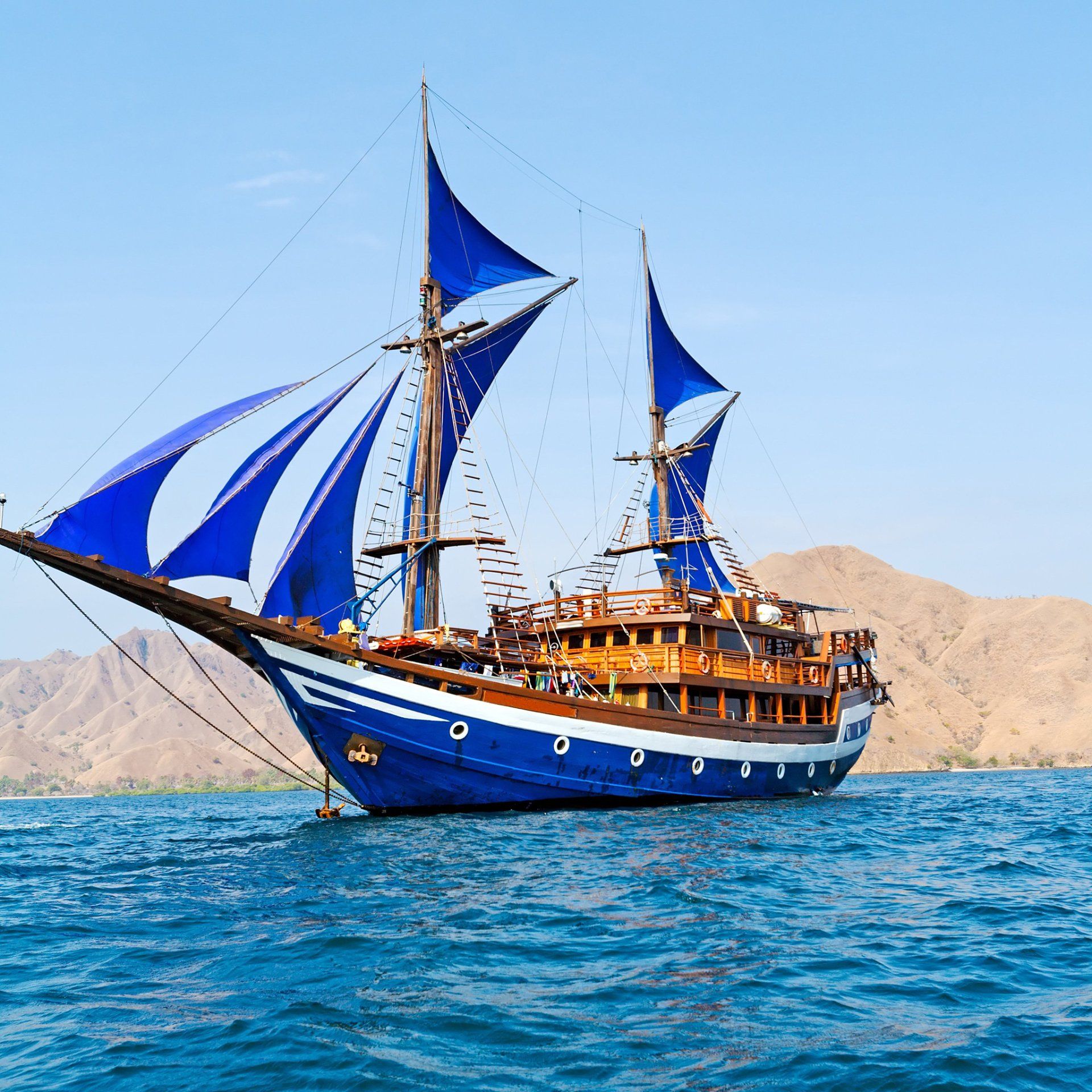 fotoVintage houten schip met blauwe zeilen in de buurt komodo island