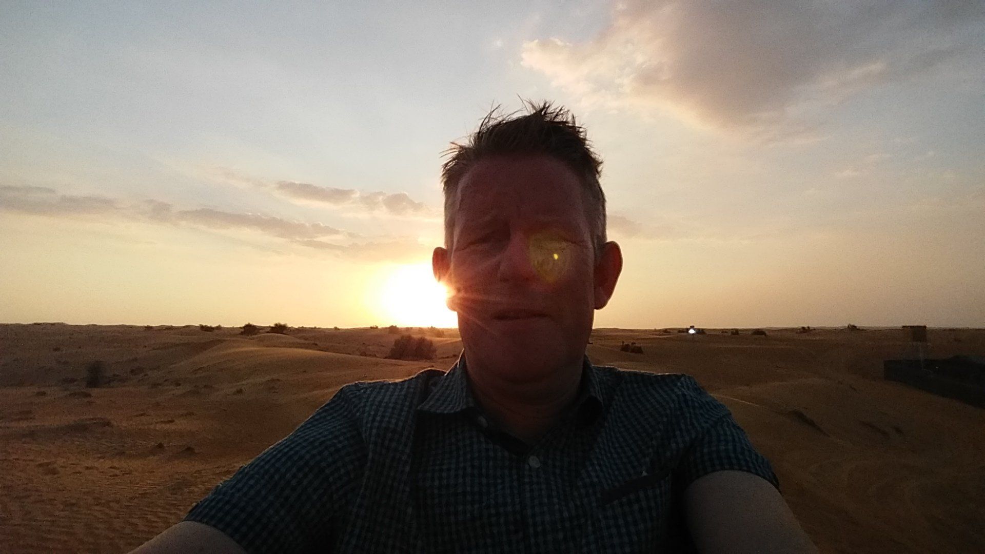 Man voor een zonsondergang boven een woestijnlandschap.