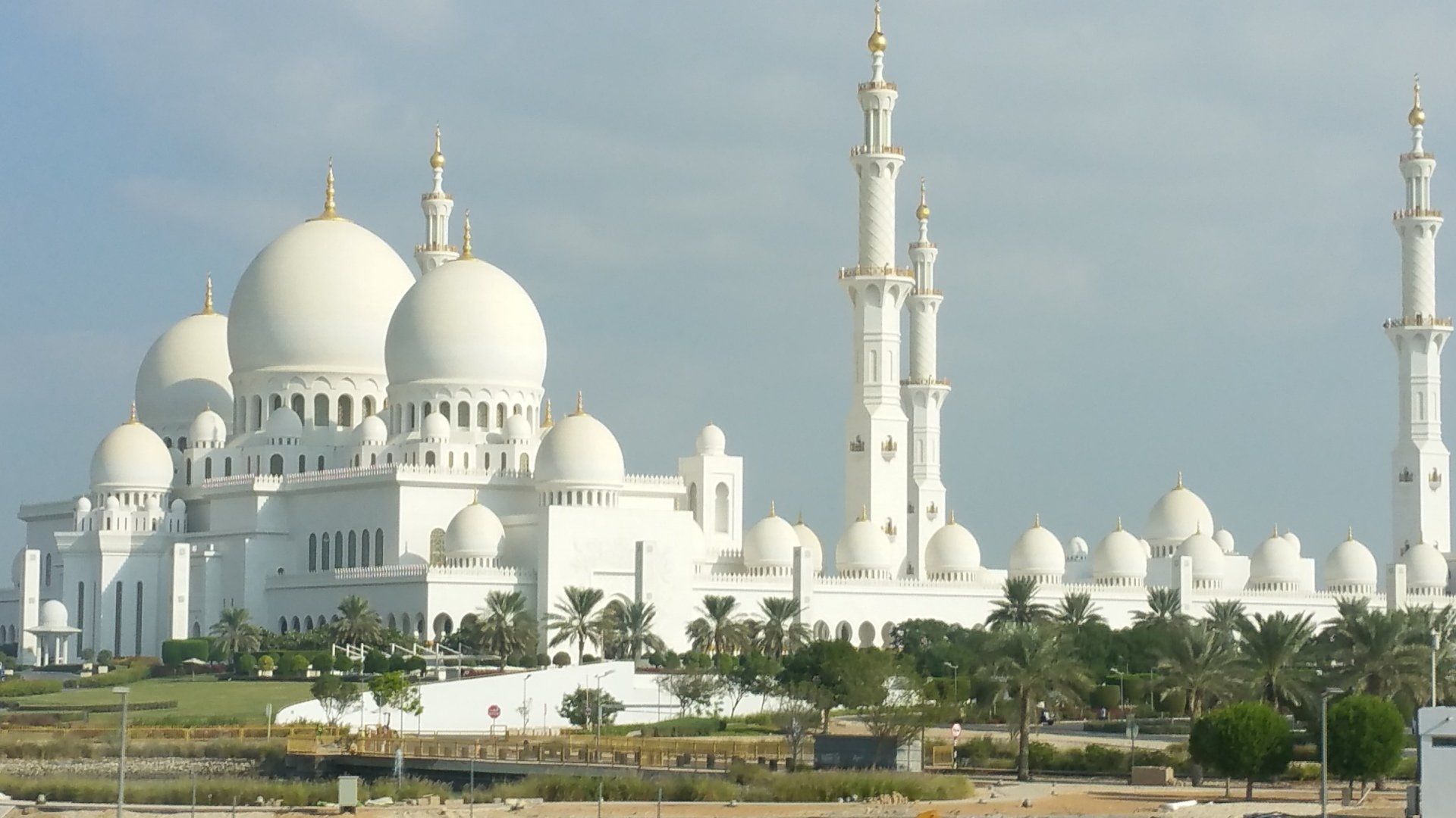 De witte Sheikh Zayed-moskee in Abu Dhabi met meerdere koepels en minaretten tegen een blauwe hemel.