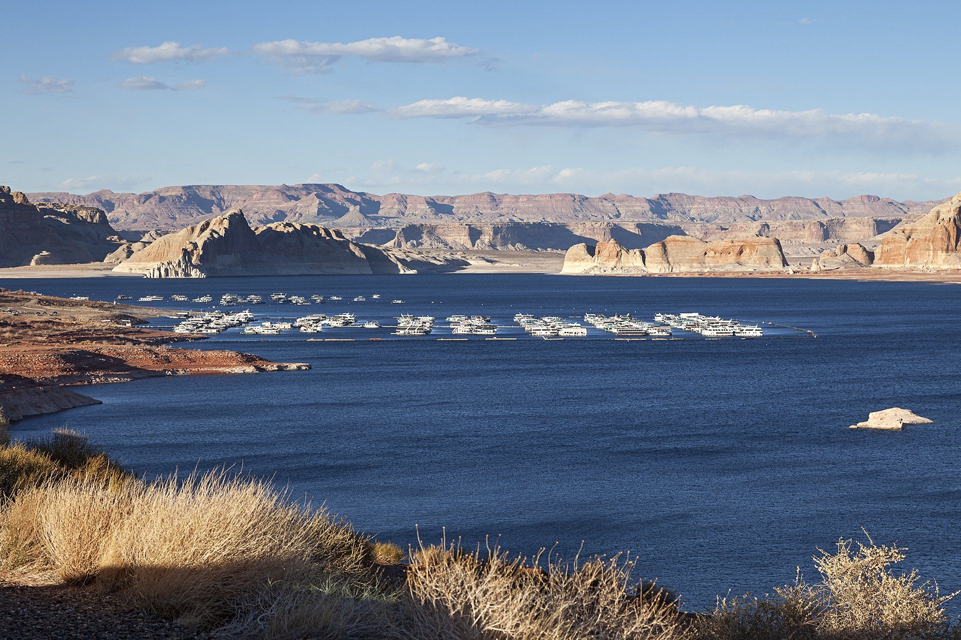 Lake Powell met rode rotsformaties en blauw water onder een blauwe hemel.