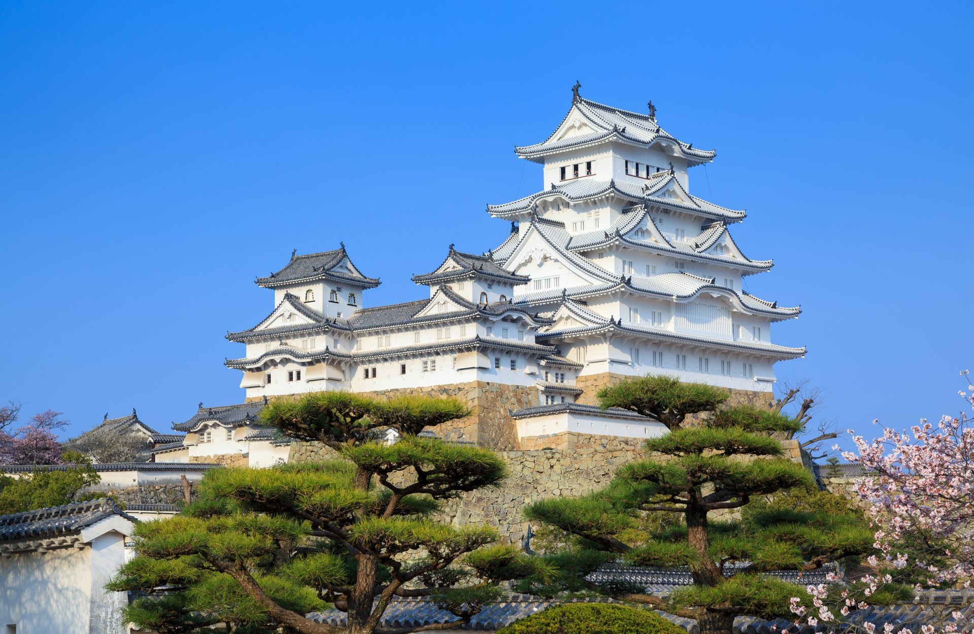 Himeji-kasteel, een wit Japans kasteel met meerdere verdiepingen, tegen een helderblauwe hemel.