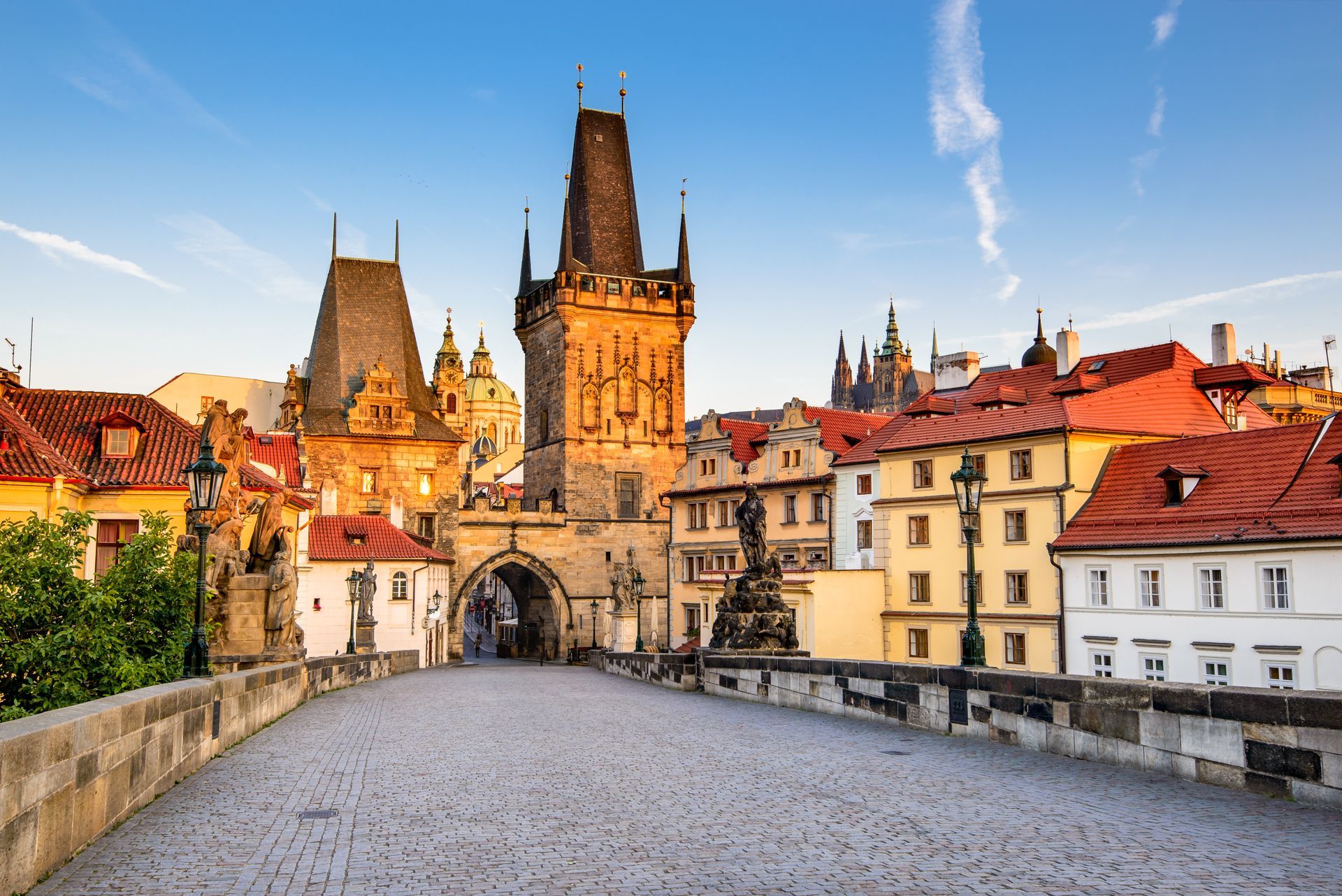 Stenen brug met torens en gebouwen in Praag, Tsjechië, onder een blauwe hemel.