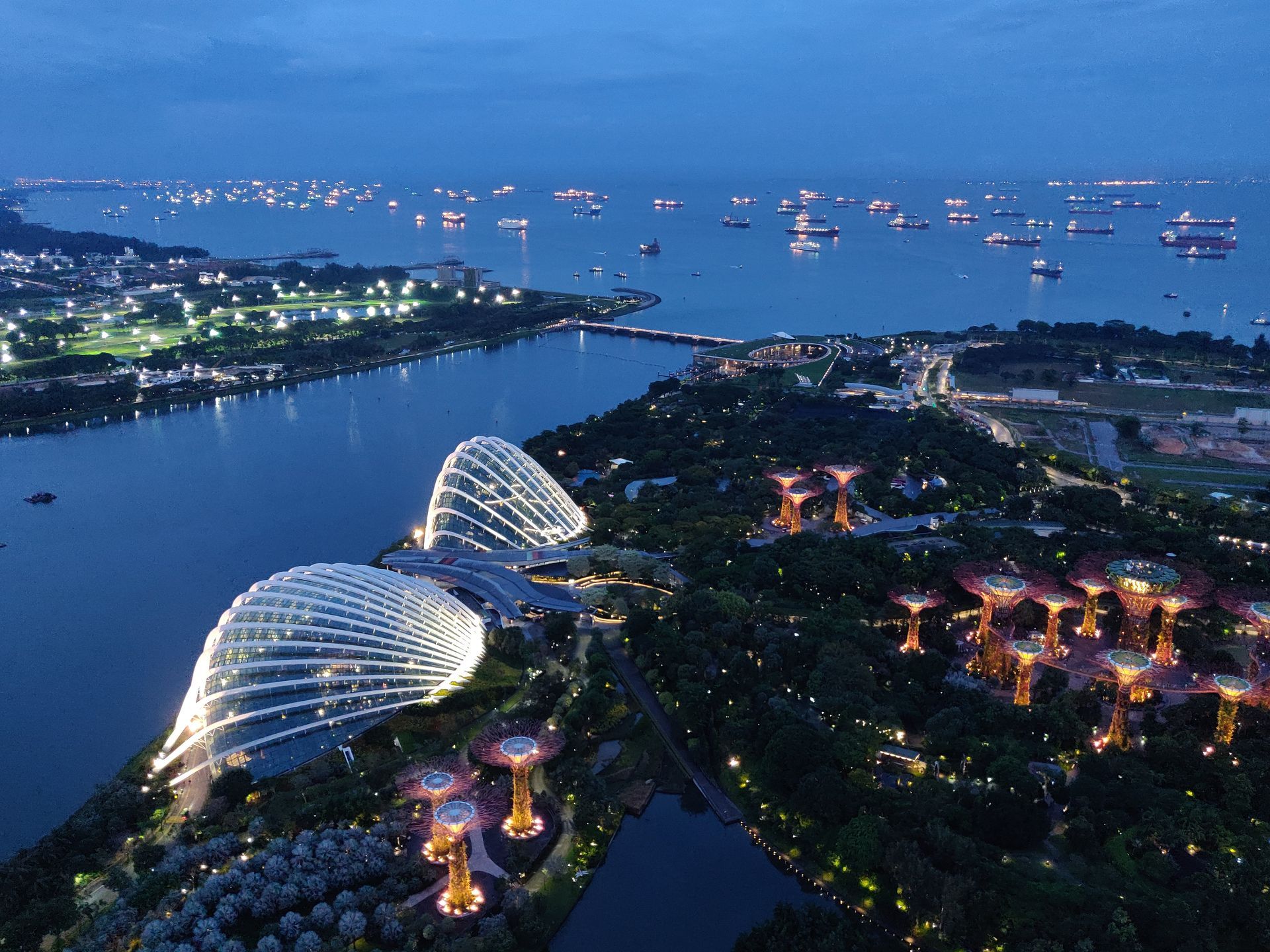 Gardens by the Bay, Singapore bij zonsondergang. Verlichte Supertrees, de waterkant en de skyline van de stad zijn zichtbaar.