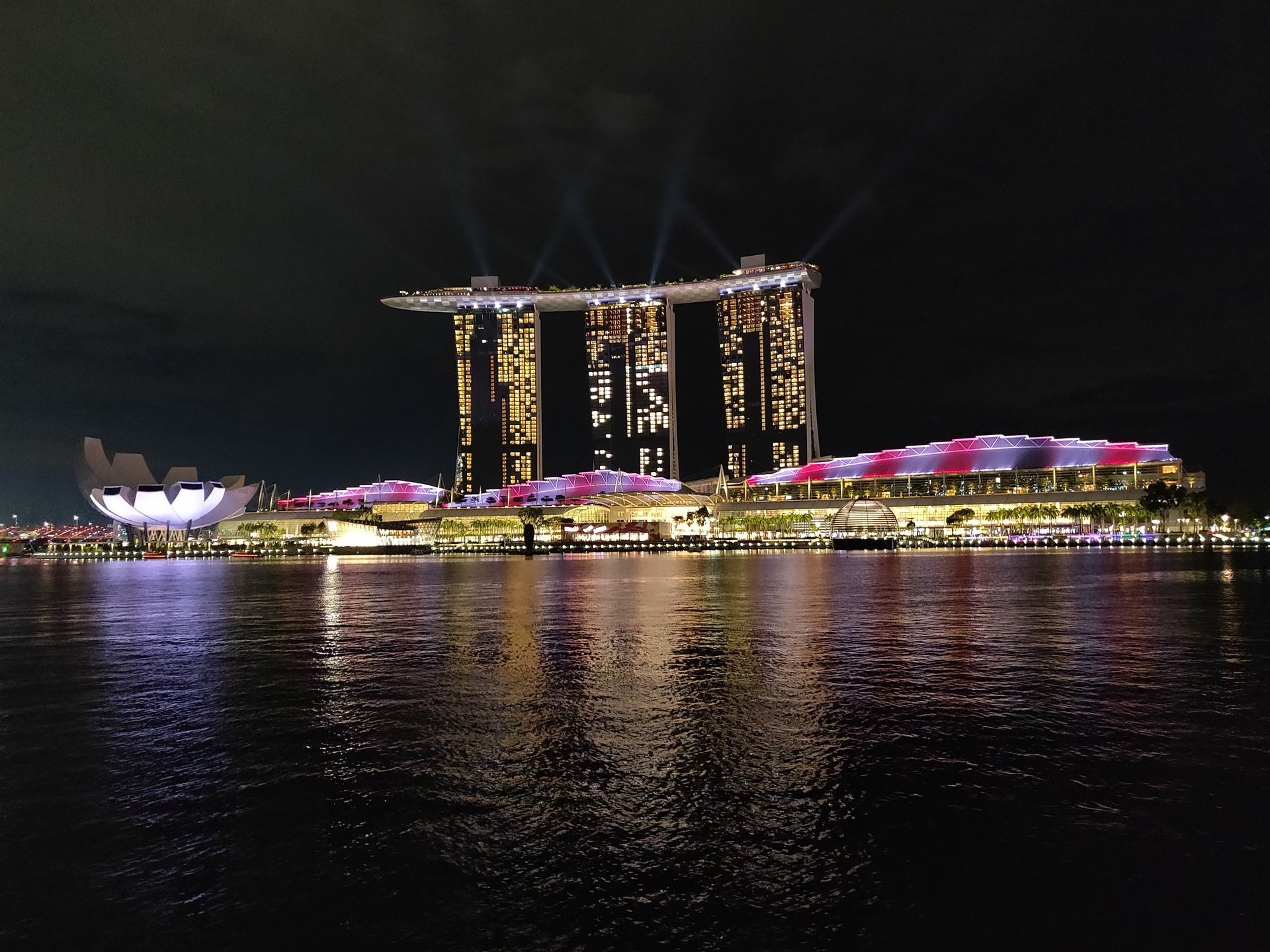 Marina Bay Sands en het ArtScience Museum 's nachts, verlicht door licht dat op het water reflecteert.