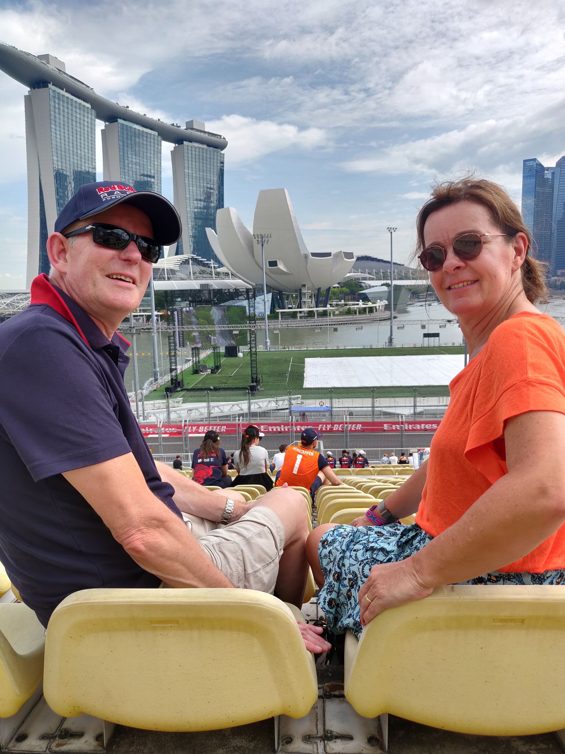 Een stel zit op tribuneplaatsen met Marina Bay Sands en het kunst- en wetenschapsmuseum op de achtergrond.