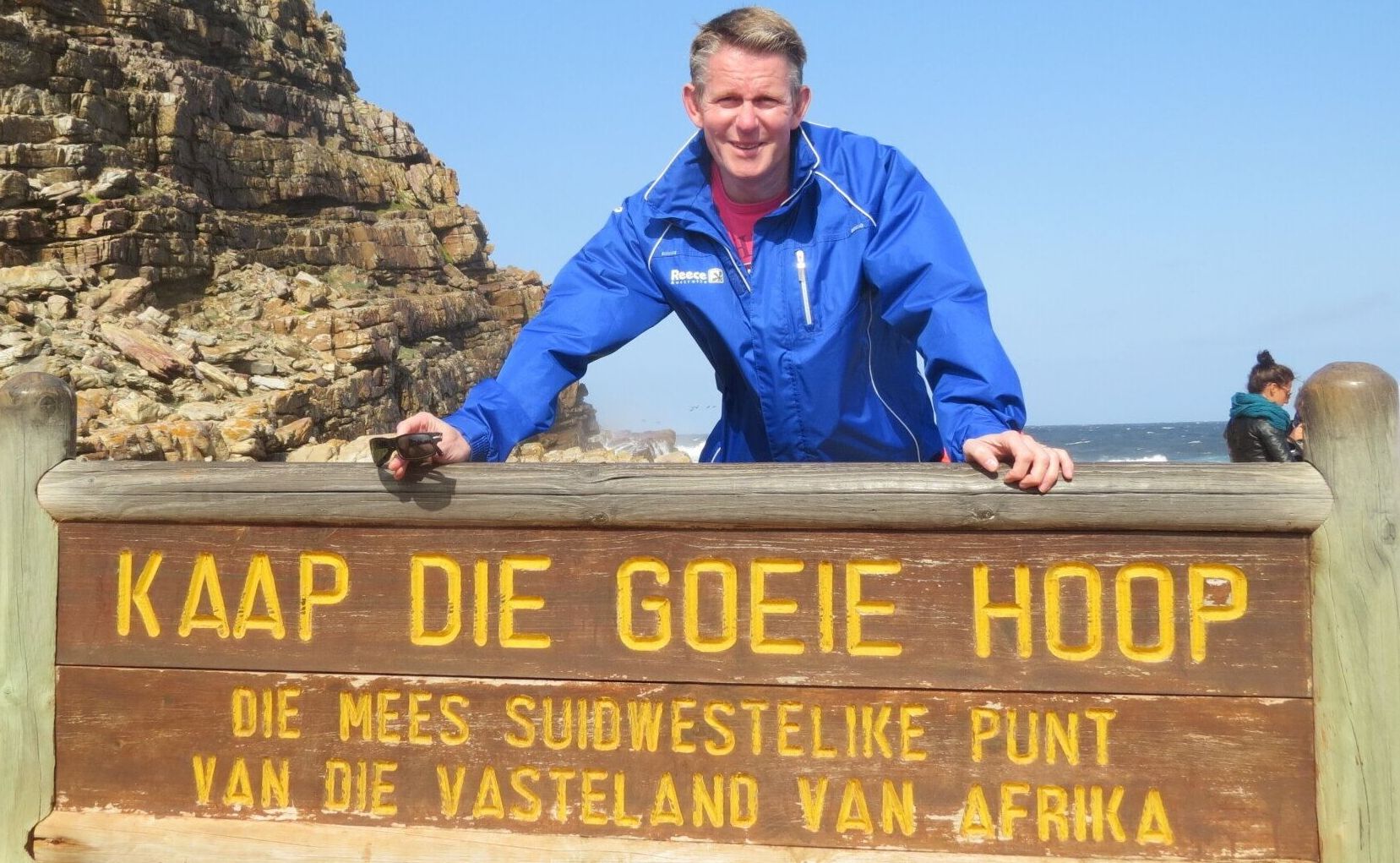 Man in blauwe jas bij het bord van Kaap de Goede Hoop.