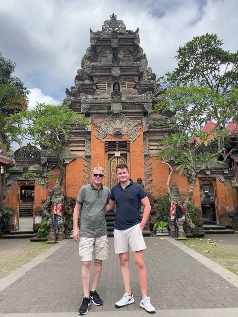 Twee mannen poseren voor een traditionele tempel op Bali, Indonesië.
