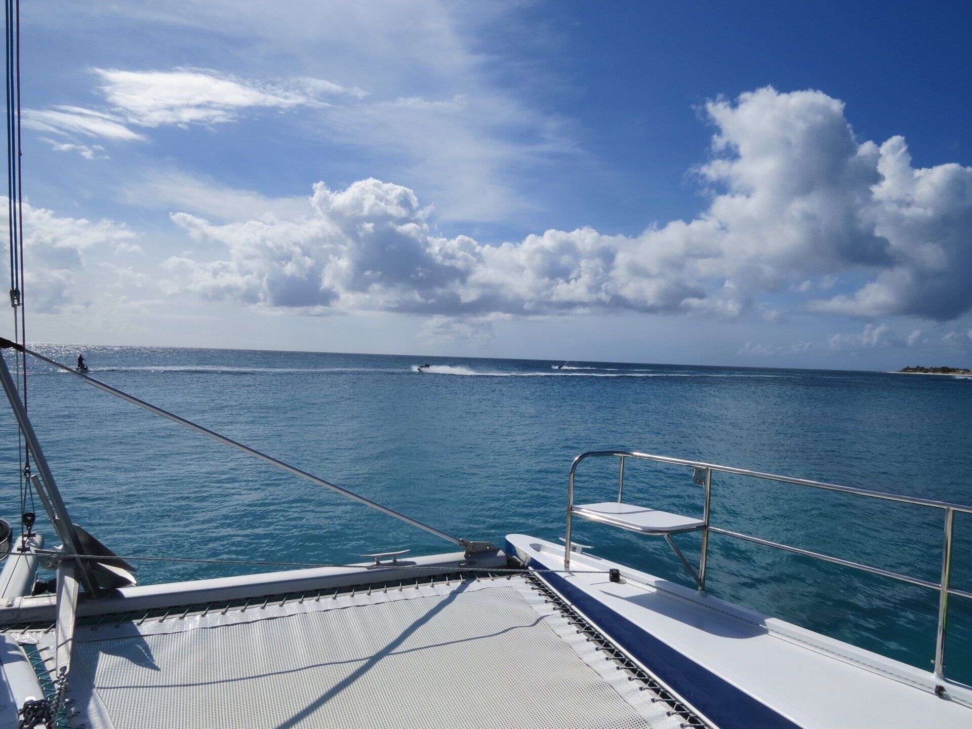 Uitzicht vanaf het dek van de catamaran op de blauwe zee en de lucht met wolken.