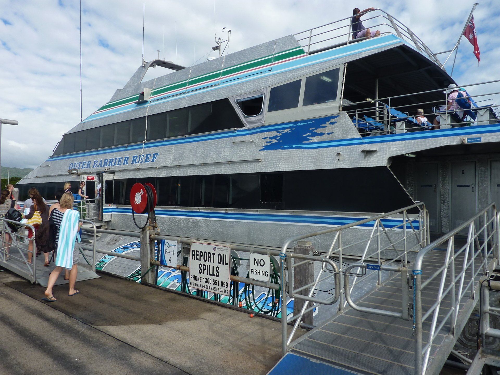 Grote boot, mensen aan boord en mensen die aan boord gaan. Zilver- en blauwtinten. Bewolkte lucht.