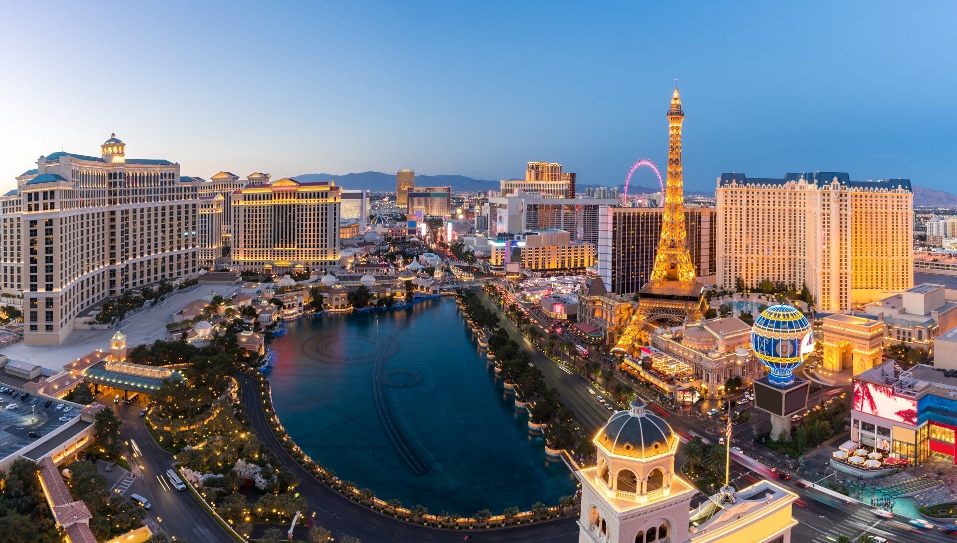 Luchtfoto van de Las Vegas Strip bij schemering met felle lichten, hotels en de replica van de Eiffeltoren.