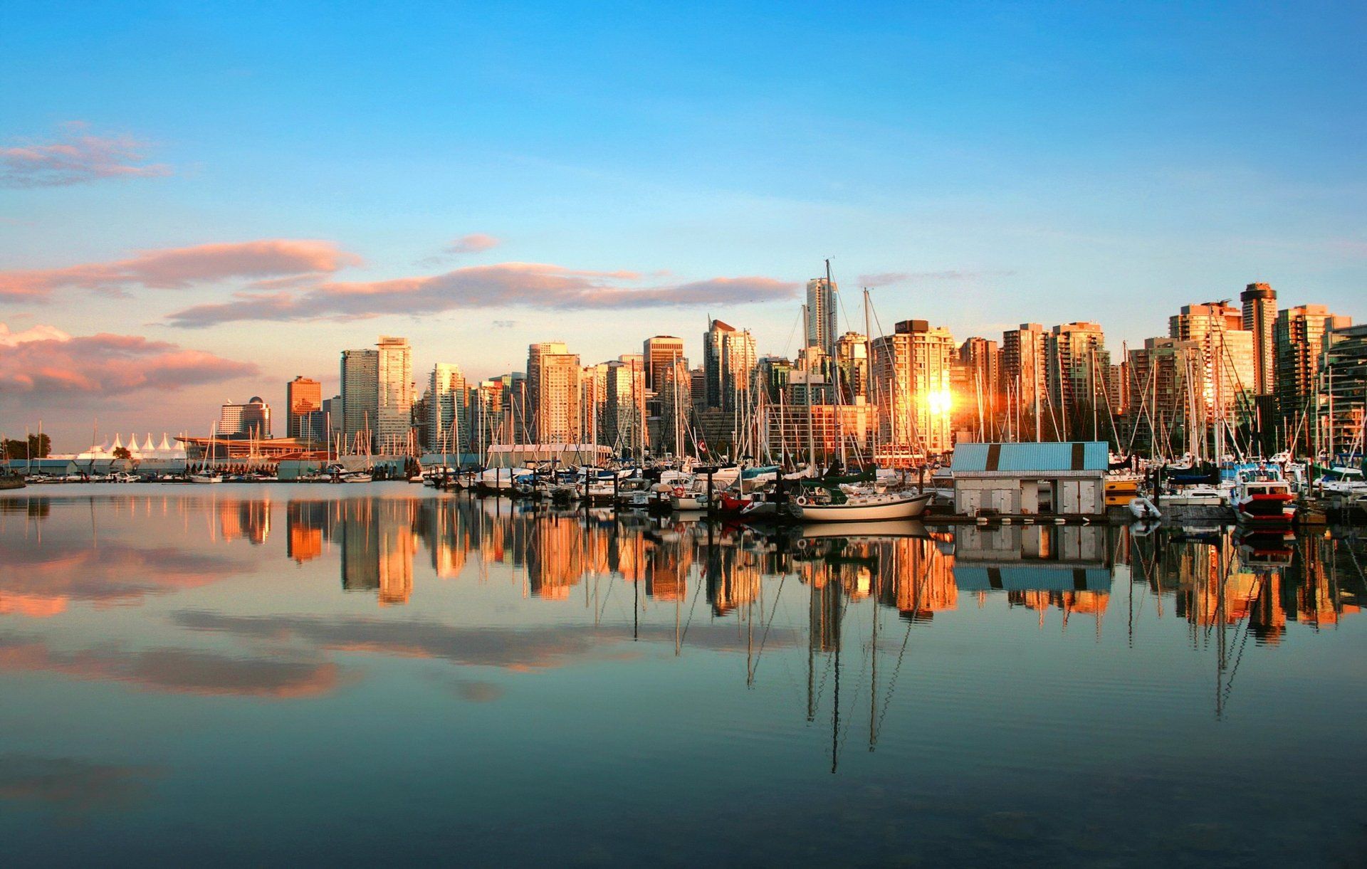 De skyline van de stad weerspiegelt zich in het water bij zonsondergang; boten op de voorgrond, gouden licht.