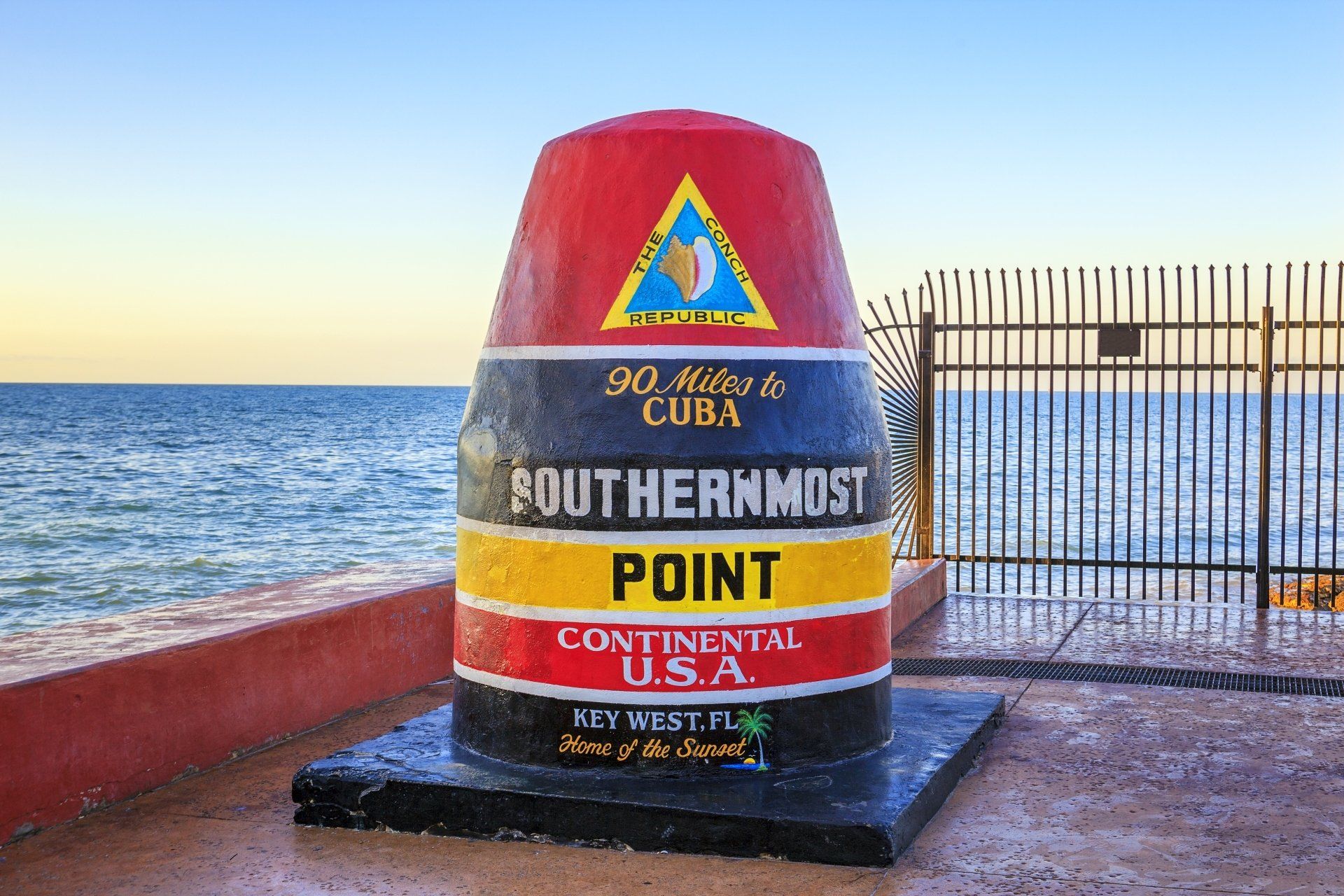 De boei van het zuidelijkste punt in Key West, Florida, in de kleuren rood, zwart, geel en wit, met de oceaan op de achtergrond.