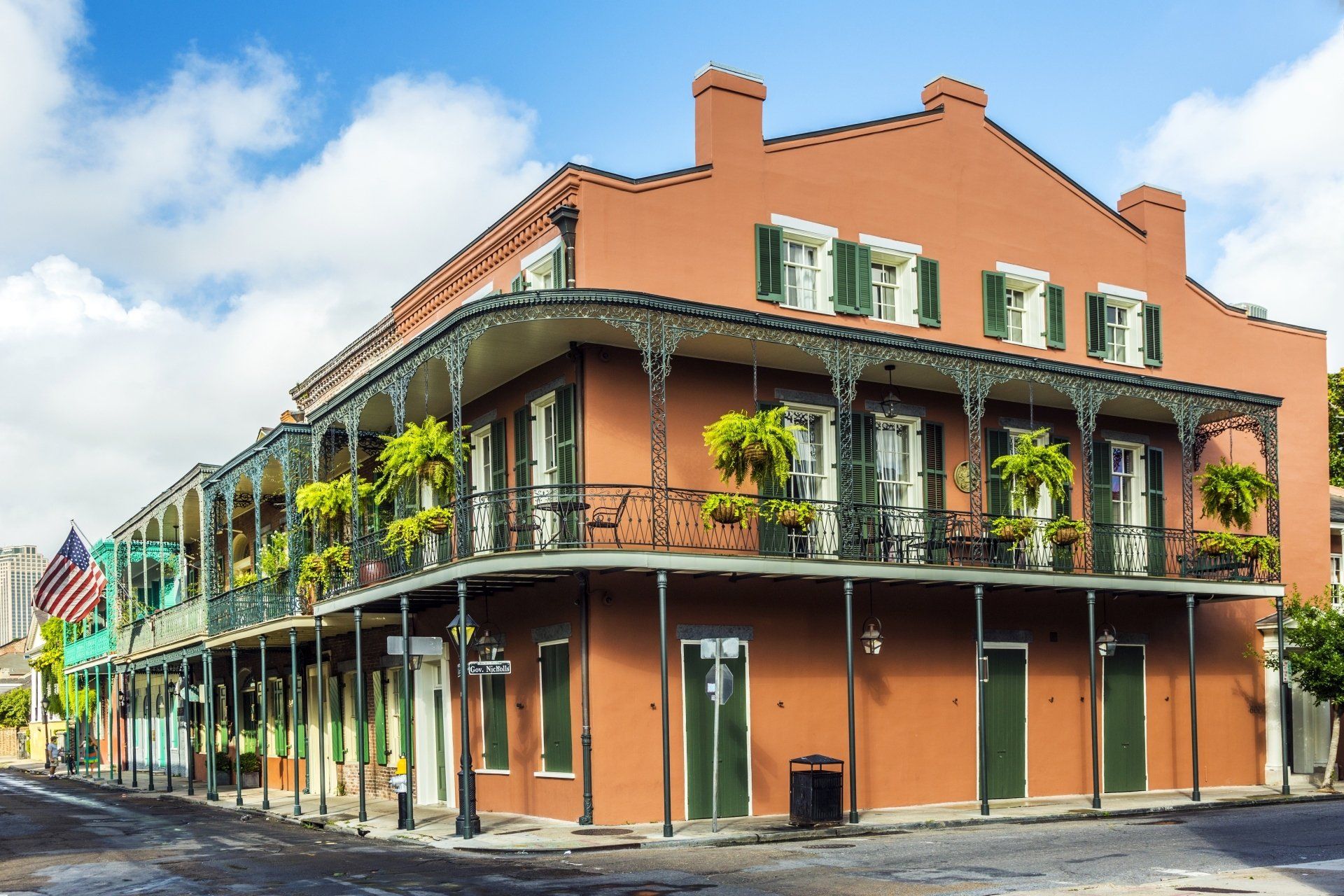 Twee verdiepingen tellend bakstenen gebouw in New Orleans met een smeedijzeren balkon en groene luiken. Er hangt een Amerikaanse vlag.