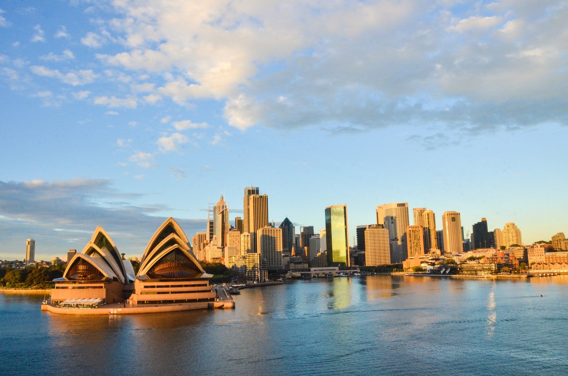Het Sydney Opera House en de skyline van de stad op een zonnige dag, gezien vanaf het water.