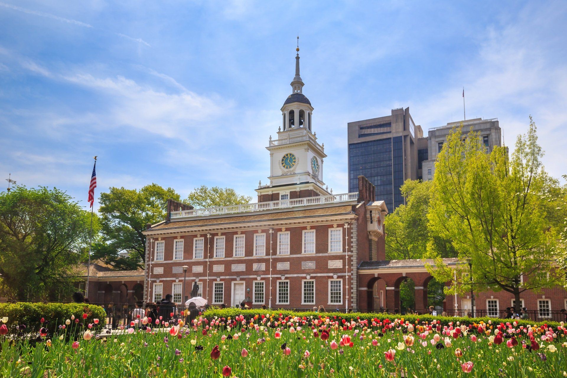 Independence Hall in Philadelphia, Pennsylvania, met een klokkentoren en een voorgrond van kleurrijke bloemen.