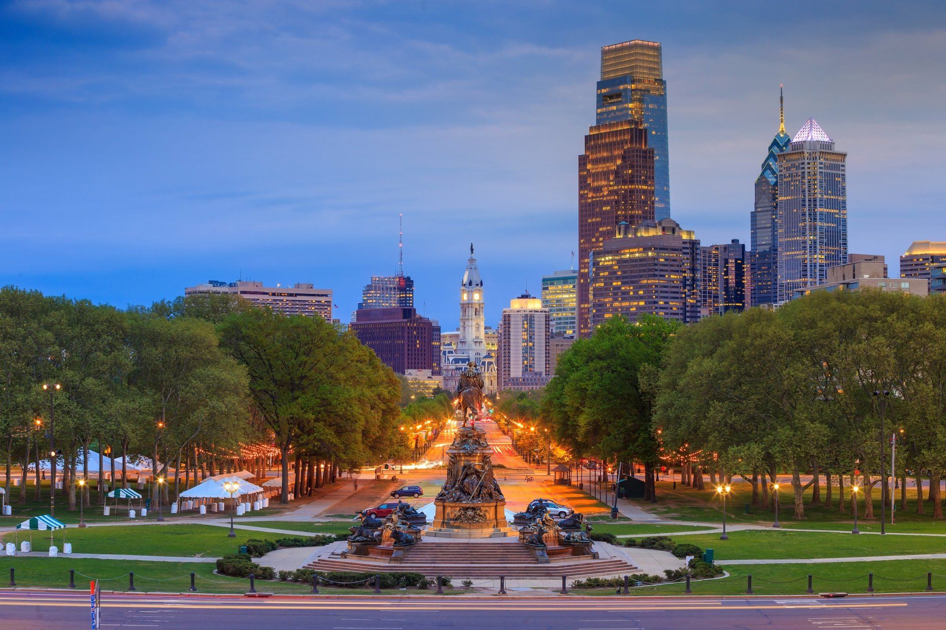 De skyline van Philadelphia met een brede parklaan, met bomen en sculpturen op de voorgrond.